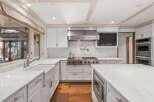 This stunning kitchen boasts a spacious island with built-in microwave, white shaker cabinets, and sleek stainless steel appliances.