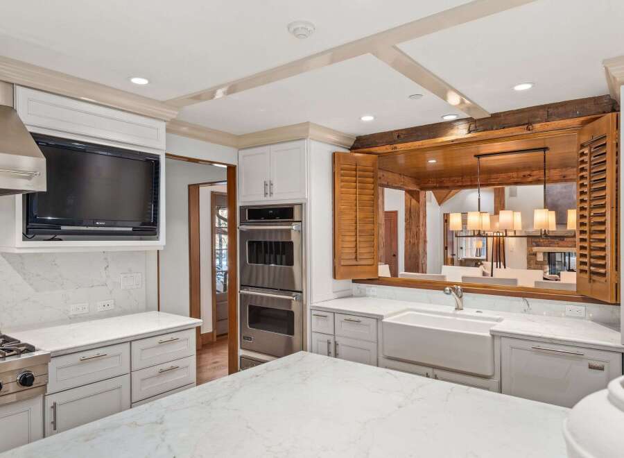 This stunning kitchen boasts a built-in TV, high-end stainless steel appliances, and custom cabinetry.