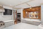 This stunning kitchen boasts a built-in TV, high-end stainless steel appliances, and custom cabinetry.