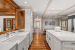 This stunning kitchen boasts a spacious island with marble countertops, white shaker cabinets, and a farmhouse sink.