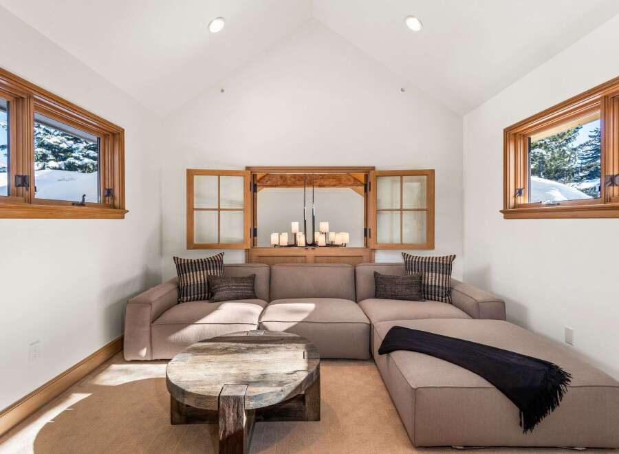 Relax in this cozy living room featuring a sectional sofa, a rustic coffee table, and large windows offering stunning mountain views.