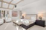 Luxurious bedroom with vaulted ceilings and exposed beams, featuring a plush bed, comfortable seating, and elegant nightstands.