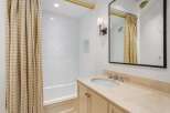 This charming bathroom boasts a classic design with beige gingham shower curtains, white subway tiles, and a beige marble countertop vanity.