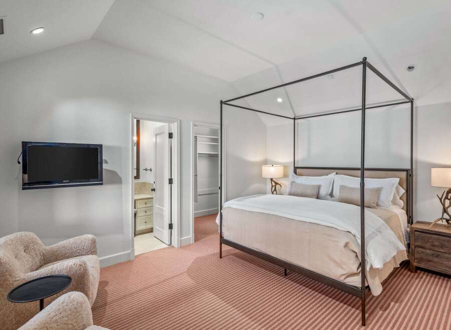 This luxurious bedroom boasts a comfortable king-size bed with a canopy, complemented by plush seating and a flat-screen TV.