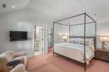 This luxurious bedroom boasts a comfortable king-size bed with a canopy, complemented by plush seating and a flat-screen TV.