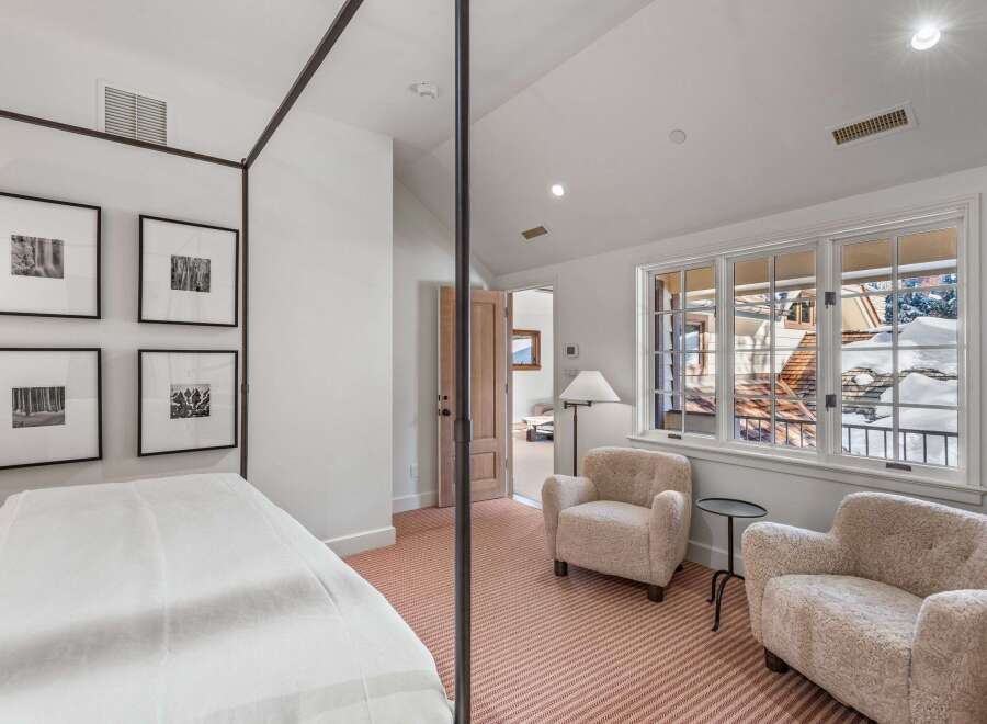 This luxurious bedroom boasts a stunning four-poster bed, plush armchairs, and large windows offering breathtaking views of a snow-covered landscape.