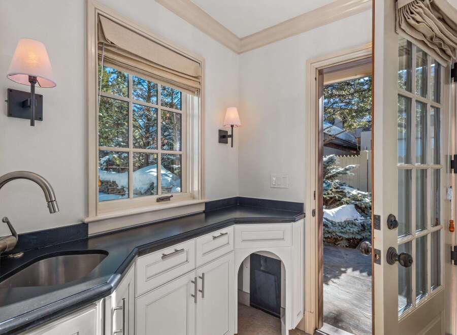 This stunning property boasts a custom-designed wet bar with a sleek black countertop and a farmhouse-style sink.