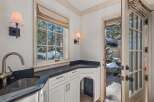 This stunning property boasts a custom-designed wet bar with a sleek black countertop and a farmhouse-style sink.