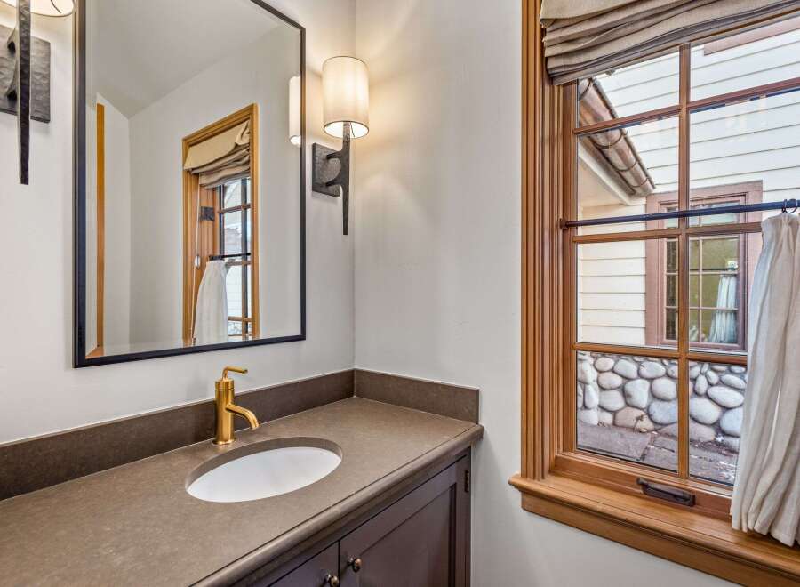 This luxurious bathroom boasts a sleek, modern design with a brown countertop and a gold faucet.