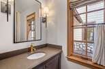 This luxurious bathroom boasts a sleek, modern design with a brown countertop and a gold faucet.