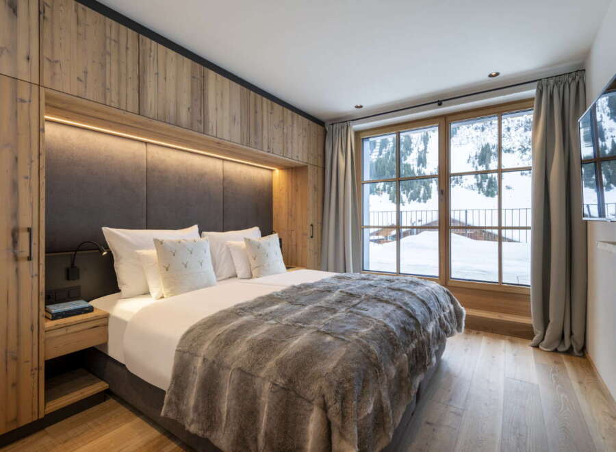 This luxurious bedroom boasts a stunning mountain view from its large window, complemented by a cozy, rustic design.