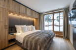 This luxurious bedroom boasts a stunning mountain view from its large window, complemented by a cozy, rustic design.