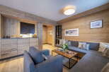 This stunning apartment boasts a spacious living area with a cozy L-shaped sofa, perfect for relaxing after a day on the slopes.