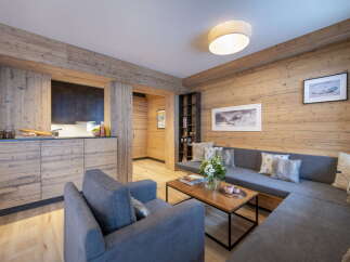 This stunning apartment boasts a spacious living area with a cozy L-shaped sofa, perfect for relaxing after a day on the slopes.