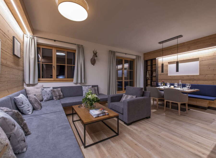 This stunning apartment boasts a spacious open-plan living area with a comfortable L-shaped sofa, perfect for relaxing after a day on the slopes.