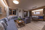 This stunning apartment boasts a spacious open-plan living area with a comfortable L-shaped sofa, perfect for relaxing after a day on the slopes.