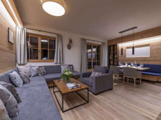 This stunning apartment boasts a spacious open-plan living area with a comfortable L-shaped sofa, perfect for relaxing after a day on the slopes.