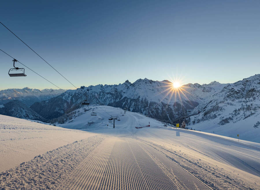 Ski resort in the mountains with a chairlift and groomed slopes.
