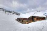 Discover this charming rustic barn nestled in a breathtaking snowy mountain landscape.