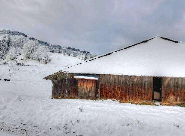 Rustic wooden barn nestled in a snowy mountain landscape.