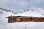 Rustic wooden barn nestled in a snowy mountainside, offering a serene escape.