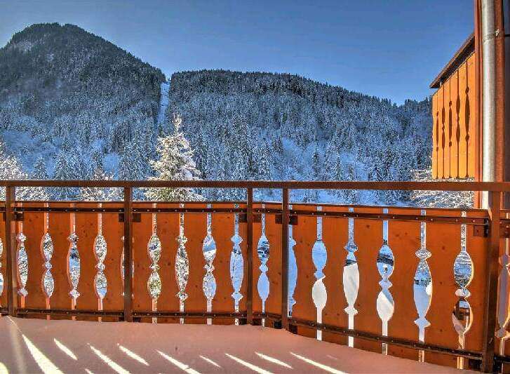 Enjoy breathtaking mountain views from your private balcony, featuring a stylish wooden railing.