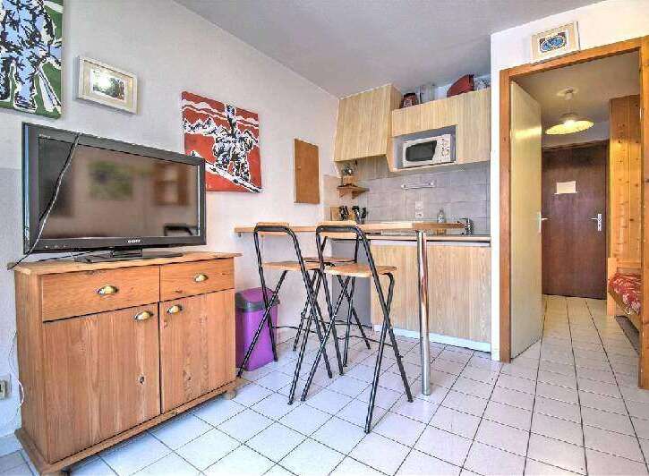 Cozy studio apartment featuring a fully equipped kitchenette, comfortable seating, and a flat-screen TV.