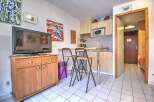 Cozy studio apartment featuring a fully equipped kitchenette, comfortable seating, and a flat-screen TV.