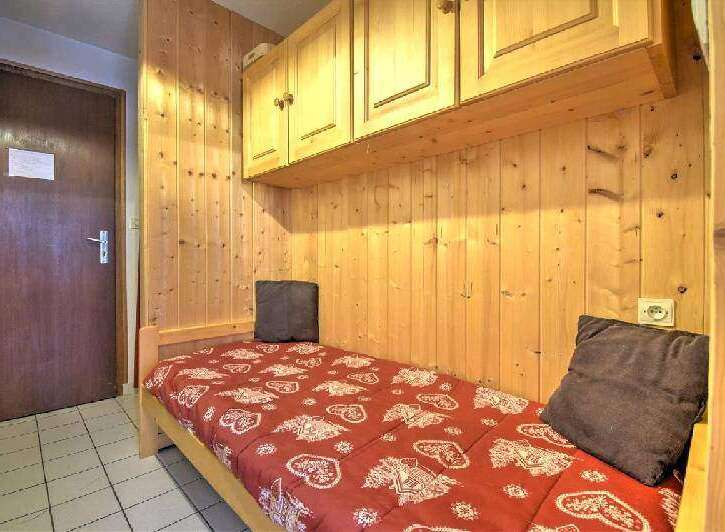 Cozy single bed tucked away in a charming wooden alcove, perfect for a peaceful night's sleep.