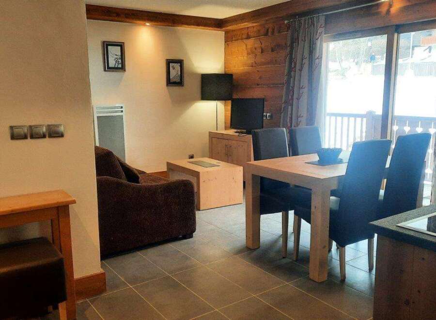 This cozy apartment boasts a well-equipped kitchen, a comfortable living area with a sofa and flat-screen TV, and a dining area perfect for enjoying meals.