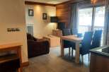 This cozy apartment boasts a well-equipped kitchen, a comfortable living area with a sofa and flat-screen TV, and a dining area perfect for enjoying meals.