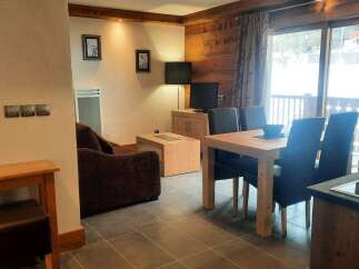 This cozy apartment boasts a well-equipped kitchen, a comfortable living area with a sofa and flat-screen TV, and a dining area perfect for enjoying meals.