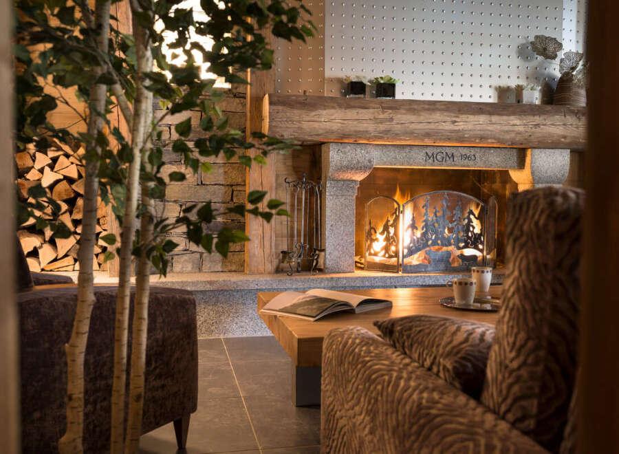 Cozy up by the fireplace in this stunning chalet, featuring a rustic stone mantelpiece and a charming wooden beam ceiling.
