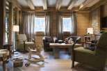 This stunning chalet boasts a spacious living area with large windows offering breathtaking views, hardwood floors, and comfortable armchairs perfect for relaxing.