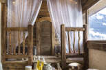 Nestled in a rustic wooden cabin, this luxurious spa boasts a tranquil treatment room with sheer curtains and soft lighting.
