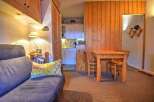 Cozy studio apartment featuring a comfortable sofa bed, a well-equipped kitchenette, and a dining area.