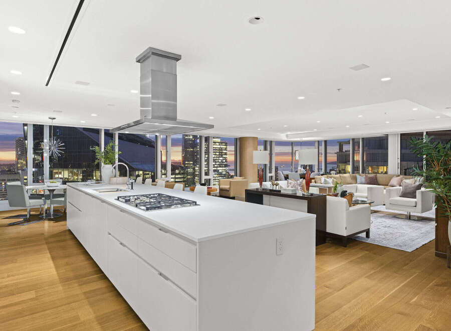 This luxurious condo boasts a stunning open-concept layout with floor-to-ceiling windows offering breathtaking city and sunset views.