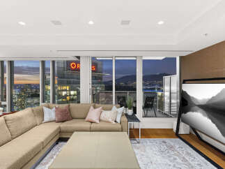 This luxurious condo boasts breathtaking panoramic city and mountain views from its floor-to-ceiling windows, creating a bright and airy living space.