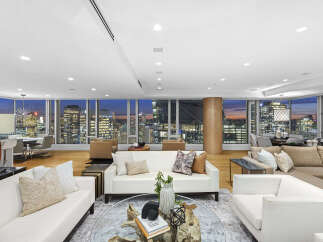 This luxurious penthouse boasts breathtaking panoramic city views from its expansive floor-to-ceiling windows, creating a bright and airy atmosphere.
