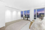 Luxurious penthouse bedroom boasts floor-to-ceiling windows showcasing breathtaking city skyline views.