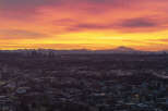 Spectacular sunrise over a sprawling cityscape, with a majestic mountain range in the distance.