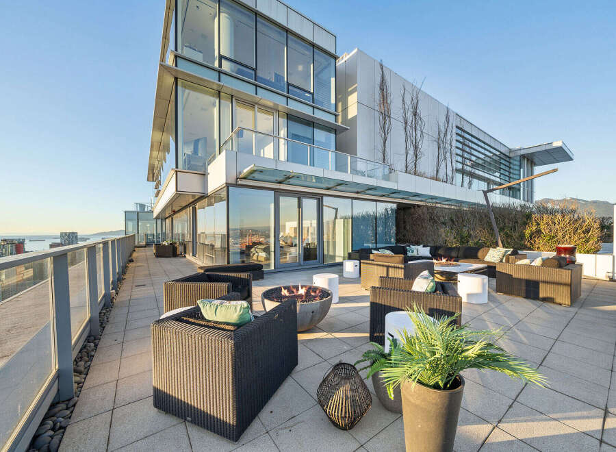 This luxurious penthouse boasts a spacious outdoor patio perfect for entertaining, complete with a fire pit, comfortable seating, and stunning city views.