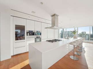 This luxurious kitchen boasts sleek white cabinetry, top-of-the-line stainless steel appliances, and a spacious island with seating.