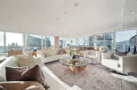 This luxurious penthouse boasts breathtaking panoramic city views from its floor-to-ceiling windows, creating an open and airy atmosphere.