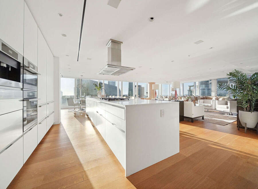 This luxurious condo boasts a stunning open-concept kitchen with top-of-the-line appliances and ample cabinetry, seamlessly flowing into a spacious living area with floor-to-ceiling windows offering breathtaking city views.
