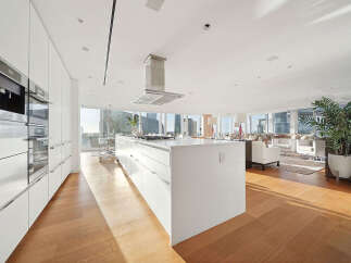 This luxurious condo boasts a stunning open-concept kitchen with top-of-the-line appliances and ample cabinetry, seamlessly flowing into a spacious living area with floor-to-ceiling windows offering breathtaking city views.