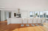 This luxurious condo boasts a stunning modern kitchen with sleek white cabinetry, high-end stainless steel appliances, and a large island with seating.