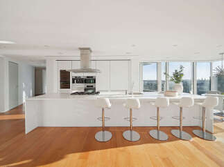 This luxurious condo boasts a stunning modern kitchen with sleek white cabinetry, high-end stainless steel appliances, and a large island with seating.