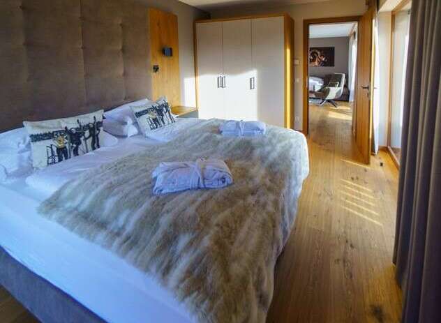 A luxurious bedroom featuring a plush bed with soft blankets and decorative pillows, complemented by a well-lit, modern wardrobe.