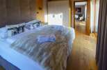 A luxurious bedroom featuring a plush bed with soft blankets and decorative pillows, complemented by a well-lit, modern wardrobe.